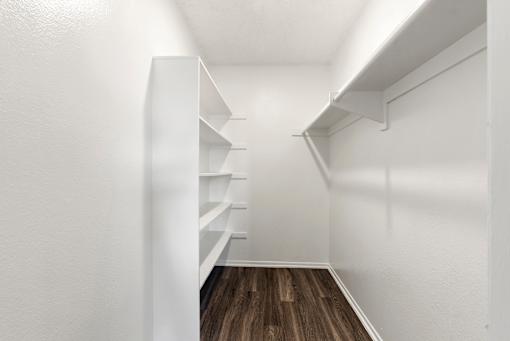 A long hallway with shelves on the side and a wooden floor.