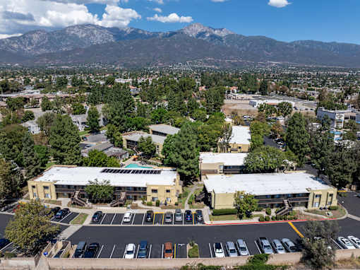 A parking lot with cars and a building in the foreground with a mountain in the background.