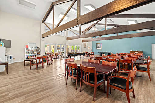 A large room with wooden floors and tables with chairs.