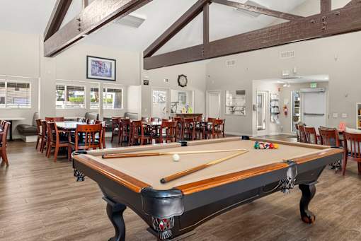 A pool table is in the middle of a room with a bar and dining area.