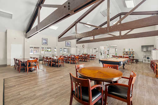 A large room with tables and chairs and a wooden ceiling.
