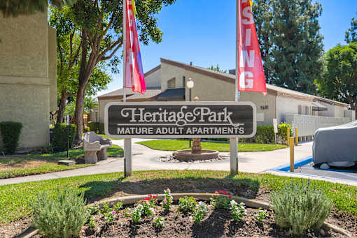 A sign for Heritage Park Mature Adult Apartments is displayed in front of a building.