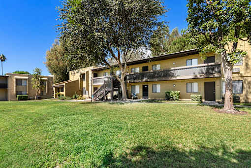 A row of houses with green lawns and trees in front.