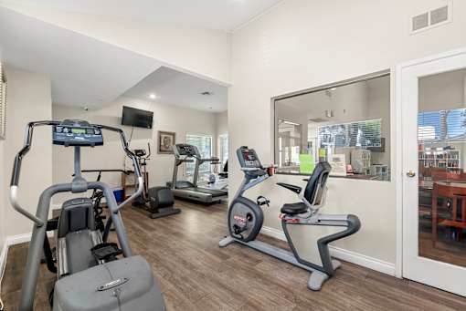 A home gym with a treadmill, elliptical trainer, and stationary bike.