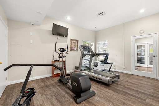 A home gym with a treadmill, elliptical trainer, and a stationary bike.
