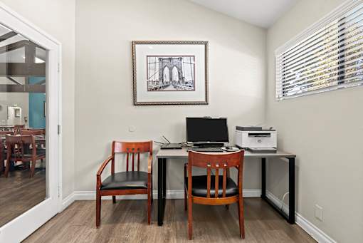 A room with a desk, chair and a picture on the wall.