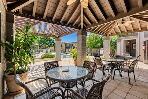 A patio with a table and chairs under a roof.
