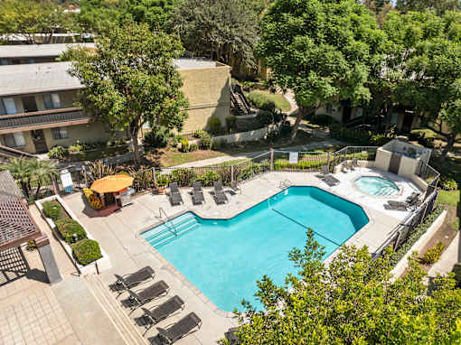 A large outdoor swimming pool surrounded by lounge chairs and trees.