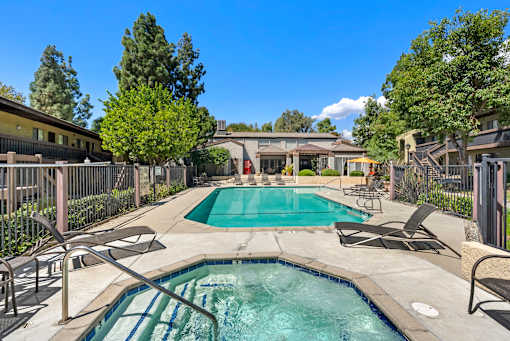 A pool surrounded by chairs and trees.