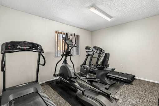 A room with a treadmill, stationary bike, and elliptical trainer.