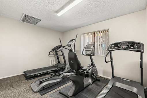A room with a treadmill, elliptical trainer and a stationary bike.