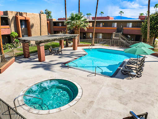 A pool with a hot tub and a table with chairs.