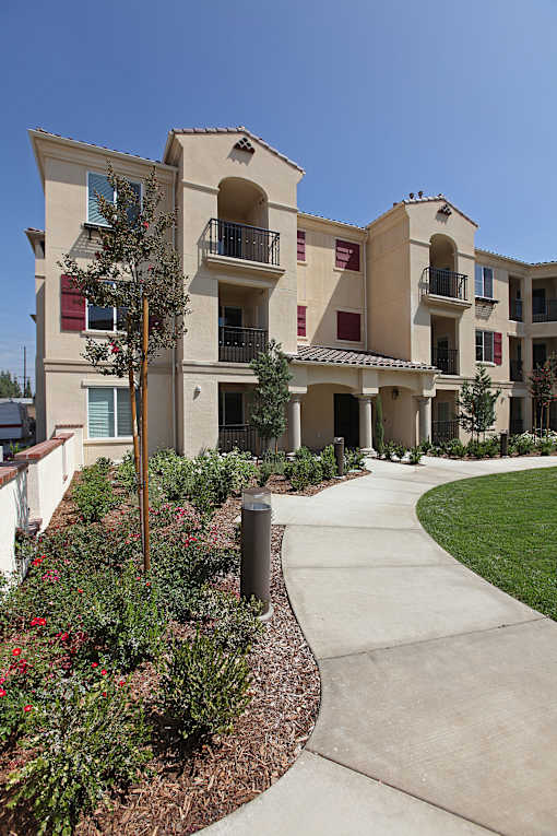 Apartment complex with a walkway and landscaping.