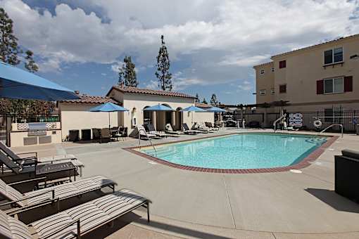 A pool with sun loungers and umbrellas in front of a building.