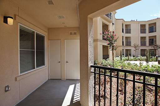 A balcony with a black railing and a view of a building with windows and balconies.