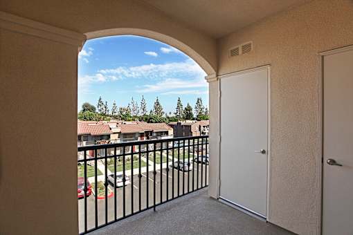 A balcony with a black railing and a view of a residential area.