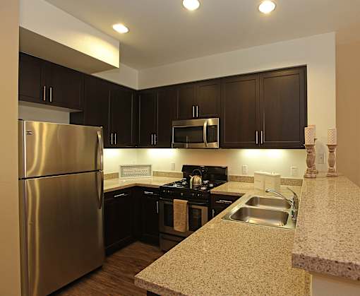 A kitchen with a stainless steel refrigerator and black cabinets.