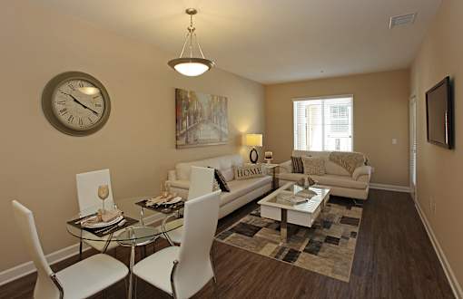 A living room with a glass table and white chairs.
