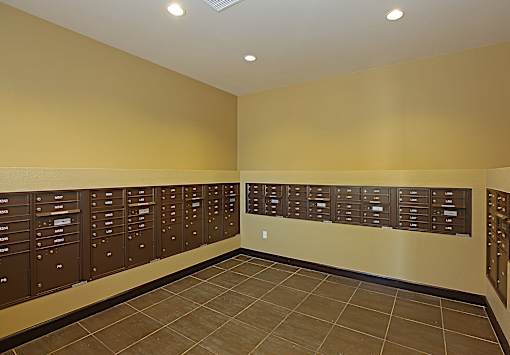 A hallway with brown lockers and a tiled floor.