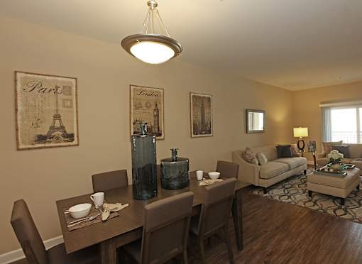 A dining room with a table set for two and a couch in the background.