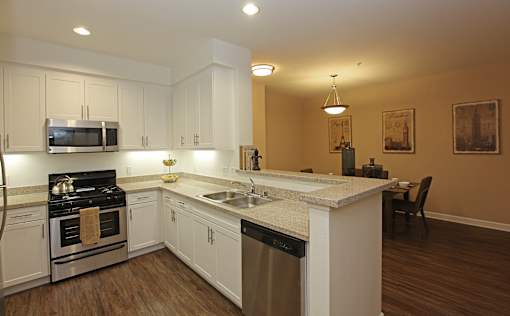 A kitchen with white cabinets and a wooden floor.