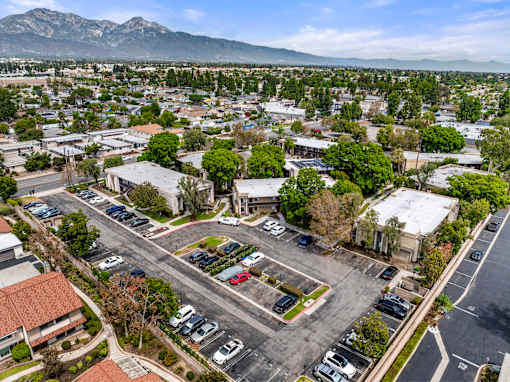 A parking lot with cars and buildings in the foreground with mountains in the background.