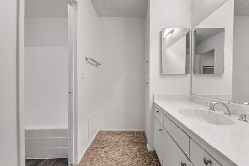 A bathroom with a sink, mirror, and a shower.