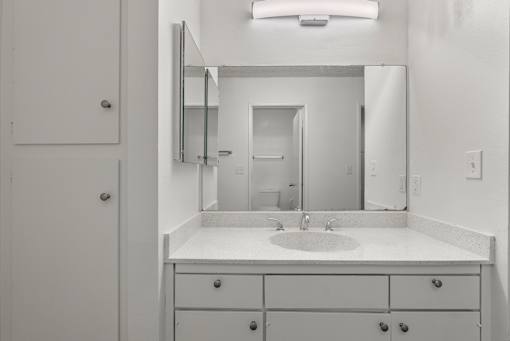A bathroom with a sink, mirror, and cabinets.