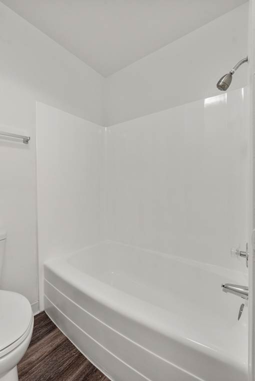 A white bathroom with a toilet and a bathtub.