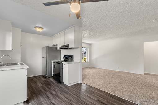 A kitchen with white cabinets and a wooden floor.
