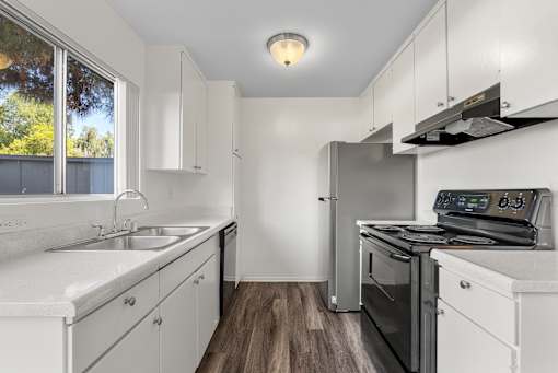 A modern kitchen with white cabinets and stainless steel appliances.
