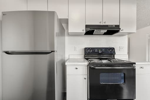 A black and white photo of a kitchen with a stove and refrigerator.
