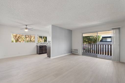 A spacious room with a ceiling fan and a view of a deck outside.