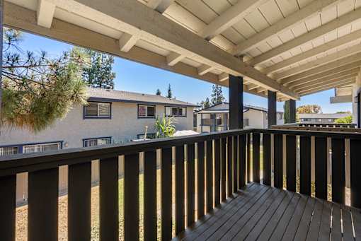 A wooden deck with a white roof and a view of a house and trees.