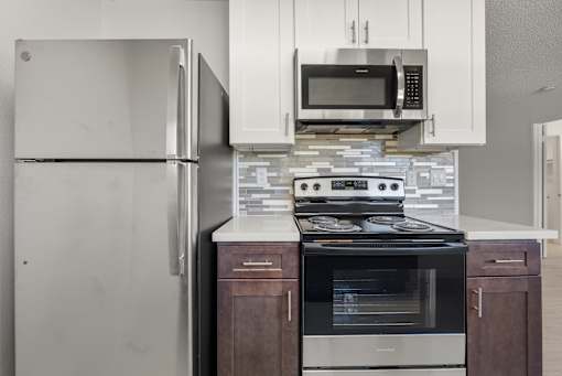A modern kitchen with a stainless steel refrigerator, microwave, and oven.