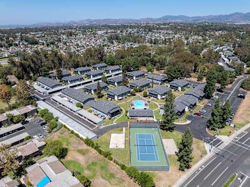 A tennis court is located in the middle of a parking lot.