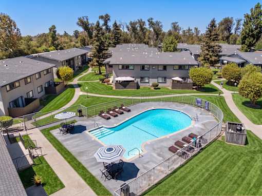 A swimming pool surrounded by a fence and chairs in a residential area.