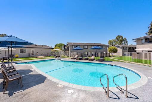 A swimming pool surrounded by a metal fence and a few chairs.