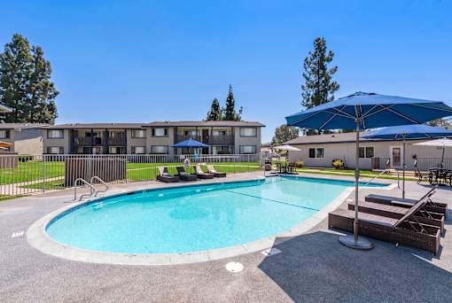 A swimming pool surrounded by a deck and a building in the background.