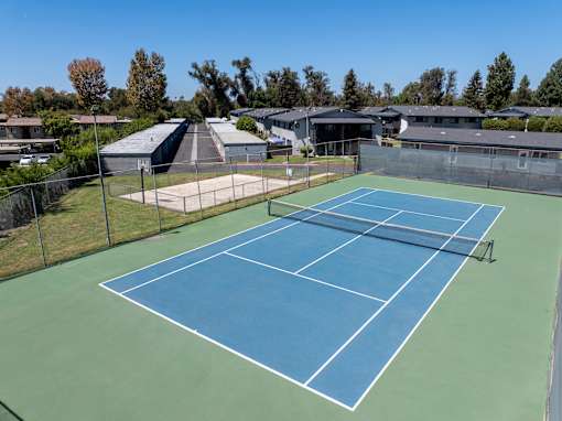 A tennis court with a green and blue surface surrounded by a fence.