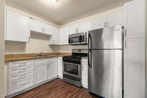 A kitchen with white cabinets and a stainless steel refrigerator.