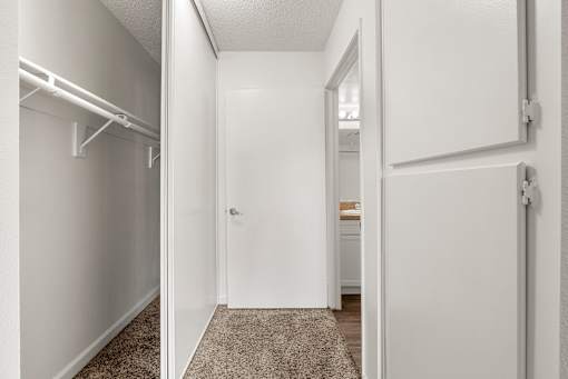 A white hallway with a door on the right and a closet on the left.
