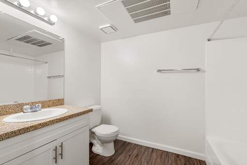 A white bathroom with a toilet, sink, and mirror.