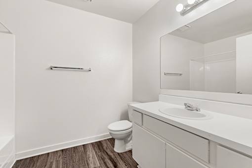A white bathroom with a toilet, sink, and mirror.