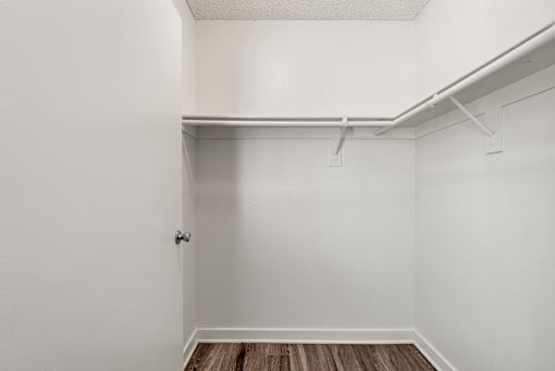 A white room with a door and a shelf.