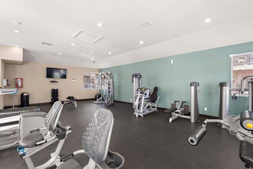 A gym with a variety of equipment including treadmills, weights, and exercise machines.