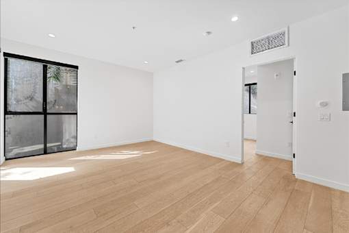 A room with wooden floors and a large window with a view of trees.