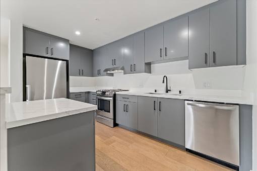 A modern kitchen with a white countertop and stainless steel appliances.