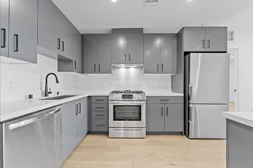 A modern kitchen with stainless steel appliances and grey cabinets.