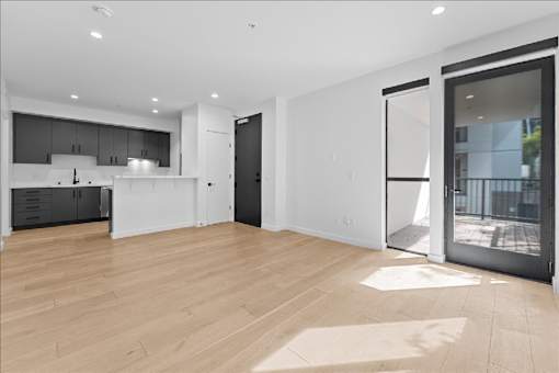 A spacious, modern kitchen with wooden floors and white walls.